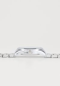 Silberne Metallarmbanduhr mit einem eleganten, achteckigen Gehäuse, Glasfront und einem Armband aus Edelstahl. Verfügt über eine runde Krone an der Seite.