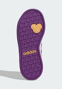Fioletowa gumowa podeszwa z wytłoczonym wzorem Myszki Miki, z złotym logo „adidas” i żółtym emblematem Myszki Miki na środku.