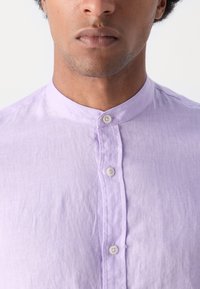 Lichtpaarse linnen shirt met een bandkraag, voorzien van een knoopsluiting aan de voorkant en subtiele textuur, die een casual en ademend ontwerp laat zien.