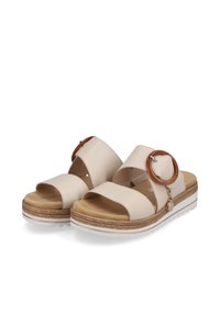 Beige Plattformsandalen mit breiten Überkreuzriemen, einer runden braunen Schnalle, strukturierter Sohle und geflochtenem Detail am Sohlenrand.