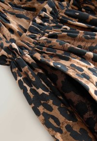 Šaty s leopardím vzorem s plisovanými detaily; obsahuje odstíny hnědé a černé na měkké tkanině; splývavý střih s texturovaným povrchem.