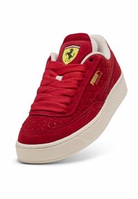 Sarkans zamšs sporta apavu modelis ar teksturētu dimanta rakstu, PUMA zīmolu un dzelteno Ferrari logo. Aprīkoti ar apaļiem šņorējumiem un baltu gumijas zoli.