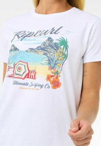 Hvid bomulds t-shirt med et farverigt strandmotiv, der viser palmer, en parasol og blomsterdetaljer. Brandlogoet er vist fremtrædende.