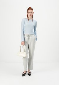 Haut à manches longues bleu clair à côte, pantalon gris à cordon, ballerines noires pointues et un petit sac à main blanc. Design minimaliste avec des textures douces.