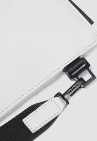 Borsa rettangolare bianca con accenti neri, materiale sintetico strutturato, cuciture visibili e dettaglio di fibbia nera sulla tracolla.