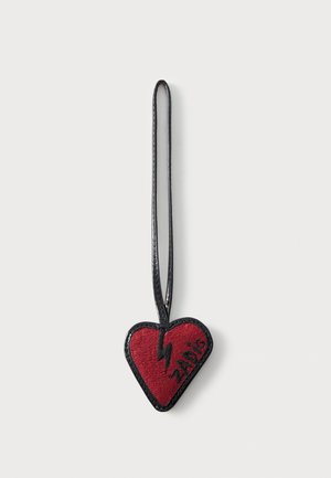 Porte-clés rouge en forme de cœur avec un éclair noir et le texte "ZADIG", attaché à une fine lanière noire en boucle.