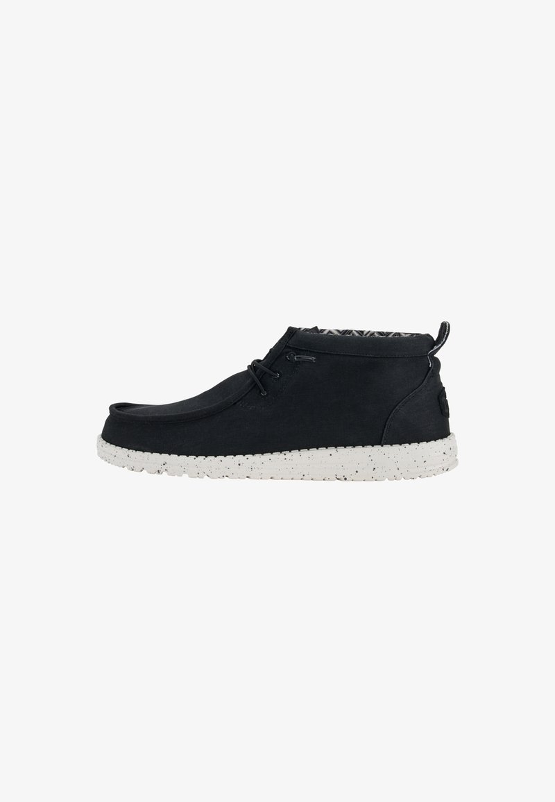 Botines negros de tela con una superficie texturada, que presentan una suela moteada blanca y un diseño de cordones. El interior tiene un forro estampado.