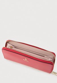 Rødt læderpung med en gylden lynlås, der har en lyserød indretning. Indvendige rum til kort og kontanter, præget brandlogo synligt.