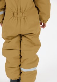 Vandtæt brun jumpsuit med elastisk talje, lange ærmer og reflekterende striber på nederste ben. Glat, slidstærk stoftekstur.