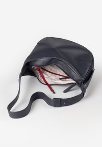Borsa a tracolla in pelle blu scuro con texture liscia e tracolla regolabile. L'interno foderato presenta un tessuto a fantasia e una tasca con zip rossa.