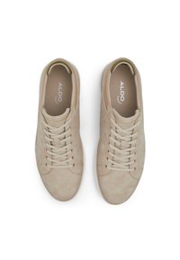 Zapatillas de ante beige con puntera redonda, cordones planos y suela de goma. Presentan un pequeño logotipo en la plantilla y una superficie lisa y texturizada.
