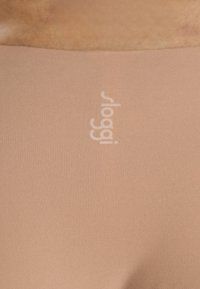 Slip hipster senza cuciture color nude con una texture morbida, caratterizzato da un logo in rilievo bianco sulla vita.