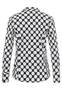 Camicia a maniche lunghe con sfondo blu navy e grandi pois bianchi, colletto e orlo curvo.