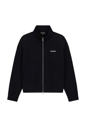 Giacca nera con zip, collo alto, tasche anteriori e piccolo logo "Guess Jeans" sul lato sinistro del petto.