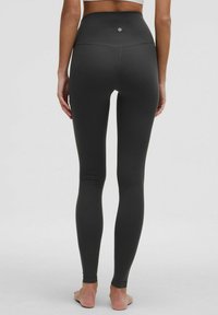 Mustat korkeavyötäröiset legginsit, joissa on sileä ja joustava materiaali. Takana oleva logo ja vartalonmyötäinen malli, joka kapenee nilkoissa.