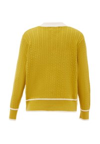 Gul ribbad tröja med krämfärgad krage och muddar. Tyget har små hål genom hela tröjan, vilket ger textur och visuell intresse.