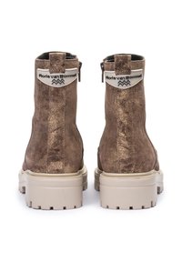 Bottines en daim marron avec une finition métallisée, dotées d'une semelle en caoutchouc beige et d'un tirant à logo au talon. Fermeture éclair à l'arrière.