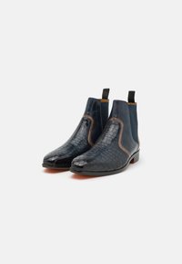 Bocanci Chelsea din piele de culoare albastru închis, cu un model texturat de crocodil, accent de culoare maro contrastant și panouri elastice pe laterale. Soli plate și tab-uri de prindere.