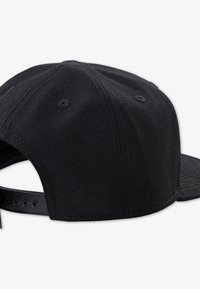 Black cap with a textured fabric, curved brim, and adjustable strap with multiple holes for size adjustment. No visible logos or embellishments.