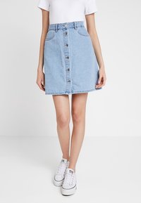 Ljust blå denimkjol med knappstängning framtill, fickor och subtila sömdetaljer. Lätt utsvängd form och midjehöjd.