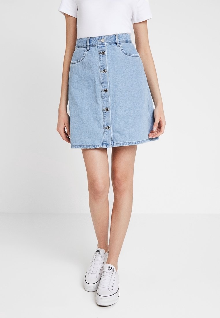 Ljust blå denimkjol med knappstängning framtill, fickor och subtila sömdetaljer. Lätt utsvängd form och midjehöjd.
