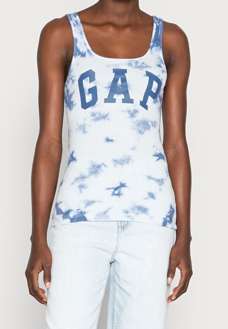 Débardeur bleu clair avec motif tie-dye blanc et logo "GAP" bleu vif sur la poitrine. Confectionné en tissu côtelé, les bretelles sont larges.