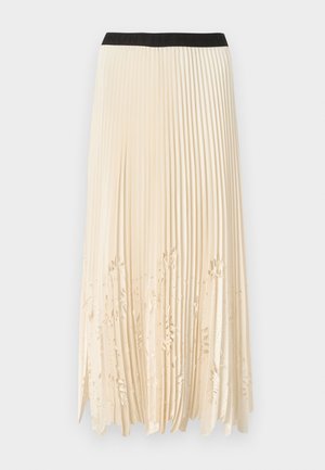 Πλισέ φούστα σε κρεμ χρώμα με μαύρη ελαστική ζώνη στη μέση· διαθέτει διακοσμητικές κοπές με λουλουδάτα μοτίβα κατά μήκος του τελειώματος για υφή και οπτικό ενδιαφέρον.