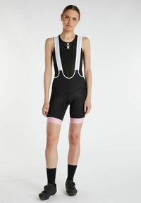 Czarne szorty rowerowe z białymi siateczkowymi ramiączkami, różowymi akcentami na nogawkach i wyściełanym siedzeniem. Wykonane z elastycznego, oddychającego materiału.