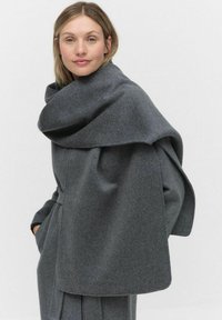 Szary płaszcz wełniany z dużym, zwisającym kołnierzem. Posiada dopasowany krój i kieszenie boczne, prezentując gładką strukturę i wyrafinowany design.