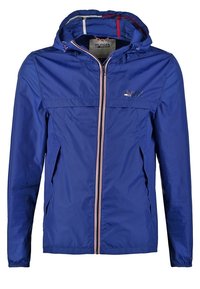 Veste légère bleue à capuche avec fermeture éclair frontale et poches latérales, avec un petit logo sur la poitrine et des poignets élastiques.