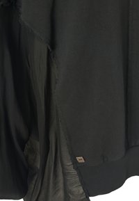 Pullover nero con design a strati. Tessuto testurizzato sul fronte, tessuto liscio sul retro, con bordi sfilacciati e un piccolo etichetta con logo.