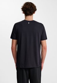 Zwarte korte mouw t-shirt met ronde hals, gemaakt van zacht materiaal. Heeft drie witte chevron-accenten op de bovenrug. Gladde textuur.