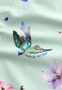 Stoff mit einem grünlichen Hintergrund und einer bunten Vogelillustration sowie floralen Mustern in Pink und Lila, markiert mit "Baker by Ted Baker."