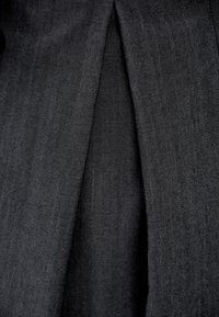 Czarna tkanina o delikatnej strukturze, z pionowym szwem i subtelnymi fałdami, nadającymi głębię i strukturę projektowi.