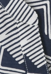 Baumwollstoff mit einem geometrischen Muster aus abwechselnd navyblauen und weißen Streifen. Nahaufnahme der Nahtdetails am Rand.