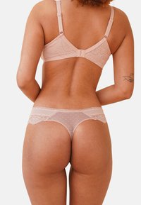 Light pink lace bra and matching thong featuring polka dots, intricate lace trim, adjustable straps, and a seamless design.
