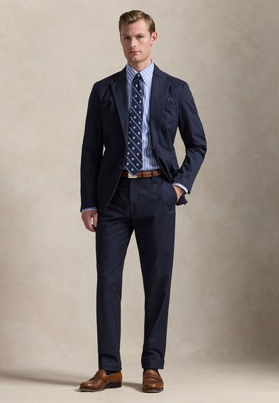 Blazer de fato azul-marinho, camisa às riscas, gravata estampada, cinto e sapatos de couro castanho. Design slim fit com texturas e cores contrastantes.