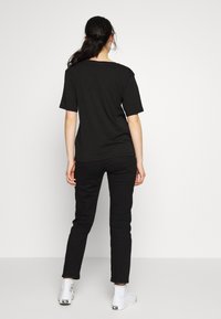 Sort T-shirt med korte ærmer og afslappet pasform, parret med sorte slim-fit bukser og hvide høj-top sneakers. Simpelt design, ingen mønstre.