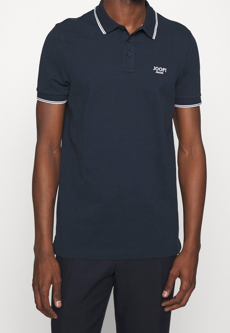 Polo marine avec passepoil blanc au col et aux manches, orné d'un petit logo brodé sur la poitrine. Fabriqué en tissu coton.