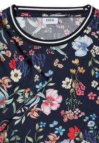 Chemise à motif floral foncé avec des fleurs colorées en rose, rouge, bleu et blanc, col rond rayé noir et blanc, et étiquette de marque "CECIL".