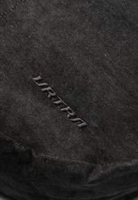 Close-up of a textured black fabric with the embroidered word "ULTRA" prominently displayed, highlighting its simplicity and design.