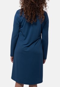 Abito blu a maniche lunghe realizzato in un tessuto morbido e liscio, con una vestibilità ampia e un orlo fino al ginocchio, caratterizzato da cuciture minime e senza motivi visibili.