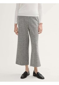 Grijze broek met een visgraatpatroon en wijde pijpen, gemaakt van textuurstof, gecombineerd met zwarte instappers. De tailleband is elastisch voor extra comfort.