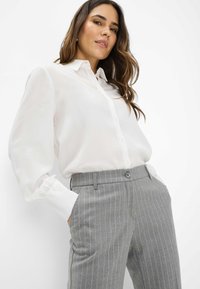Witte button-up shirt met lange, licht geraffineerde mouwen, gecombineerd met grijze broek met streepjes en een tailleband met knoop en zijzakken.