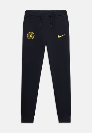 Čierne tepláky Chelsea FC so žltým klubovým erbom na ľavom stehne a žltým logom Nike na pravom stehne, elastický pás sťahovacie šnúrky.