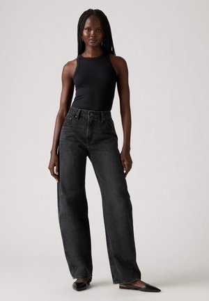 Sort ribbet tank top parret med høj talje, vidde ben sorte denim jeans. Glat tekstur, minimalistisk design og diskret detaljering.