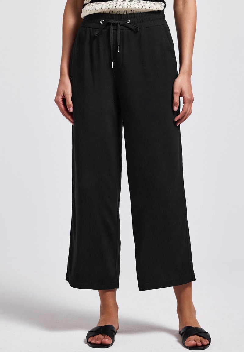 Pantalons larges noirs avec une taille élastique et un cordon de serrage réglable. Tissu lisse avec une coupe décontractée et sans motifs visibles.