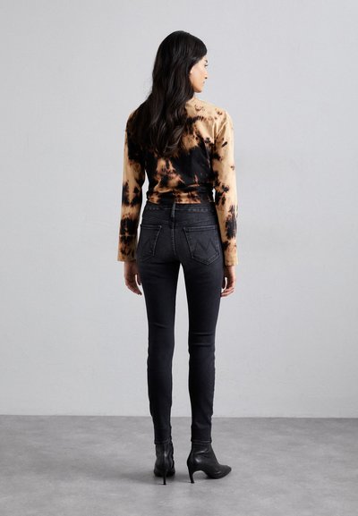 Sorte skinny jeans med højt liv og detaljer ved baglommerne, parret med en langærmet top i brun og sort tie-dye.