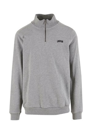 Šedá zipová mikina vyrobená z měkké látky, s vysokým límcem, žebrovanými manžetami a malým logem "UNFAIR" na hrudi.