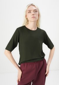 Tmavě zelené tričko s krátkým rukávem a kulatým výstřihem, vyrobené z měkké látky, uvolněný střih, doplněné kalhotami s elastickým pasem v barvě burgundy.